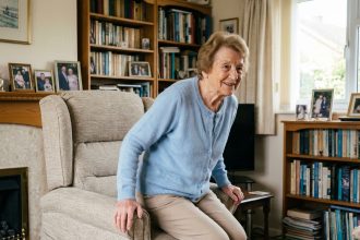 Femme senior assise dans un fauteuil moderne souriante